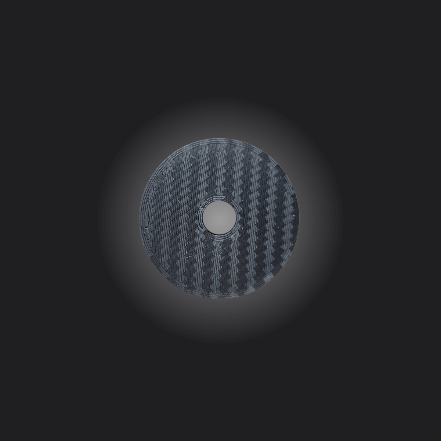Close-up of a circular carbon fiber disc, showcasing a textured finish, ideal for gaming or automotive setups.